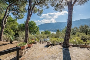 Un sentier pavé de pierres mène à un belvédère offrant une vue panoramique sur un lac et des montagnes.