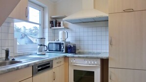 Eine kleine Küche mit Mikrowelle, Kaffeemaschine und Backofen.