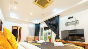 Habitación de hotel moderna con una cama grande, un televisor de pantalla plana y un balcón con cortinas.