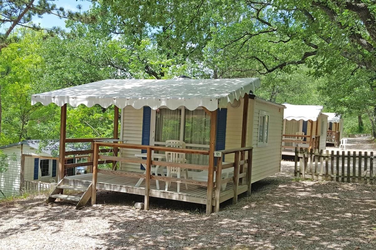 Een rij houten hutten met een overdekte veranda en een kleine trap naar de ingang.