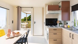 Una cocina moderna con estufa a gas, armarios de madera y un comedor con mesa y sillas.