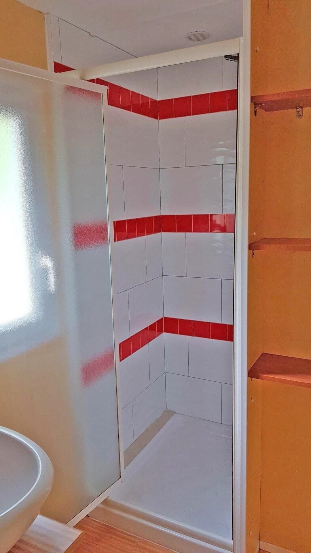 A bathroom with white and red tiles, a wooden door, and a white sink.