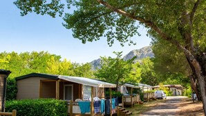 Un conjunto de casas móviles de madera con porches adosados, ubicadas en una zona boscosa con montañas al fondo.