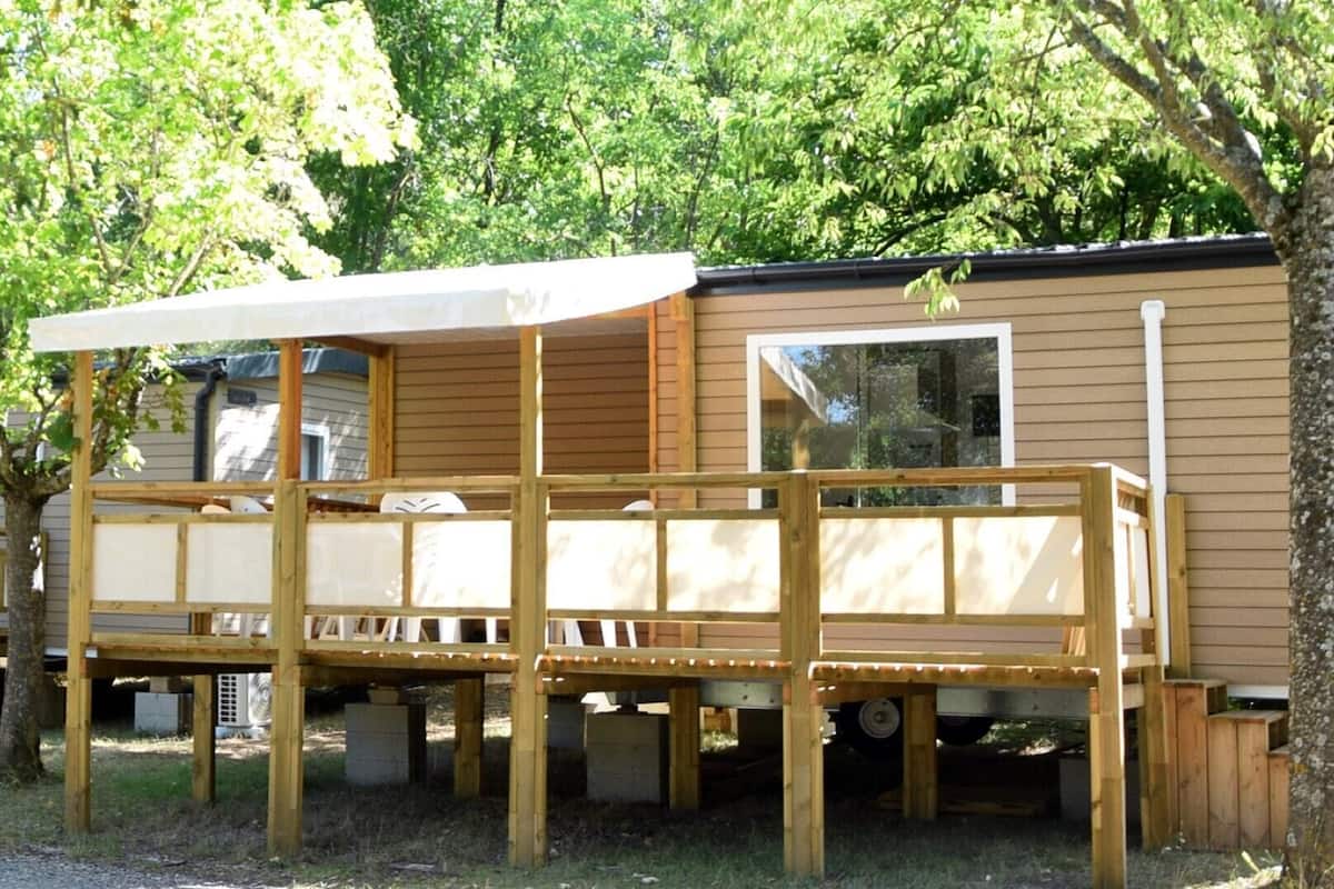 Een stacaravan met een houten terras en een overdekte patio.