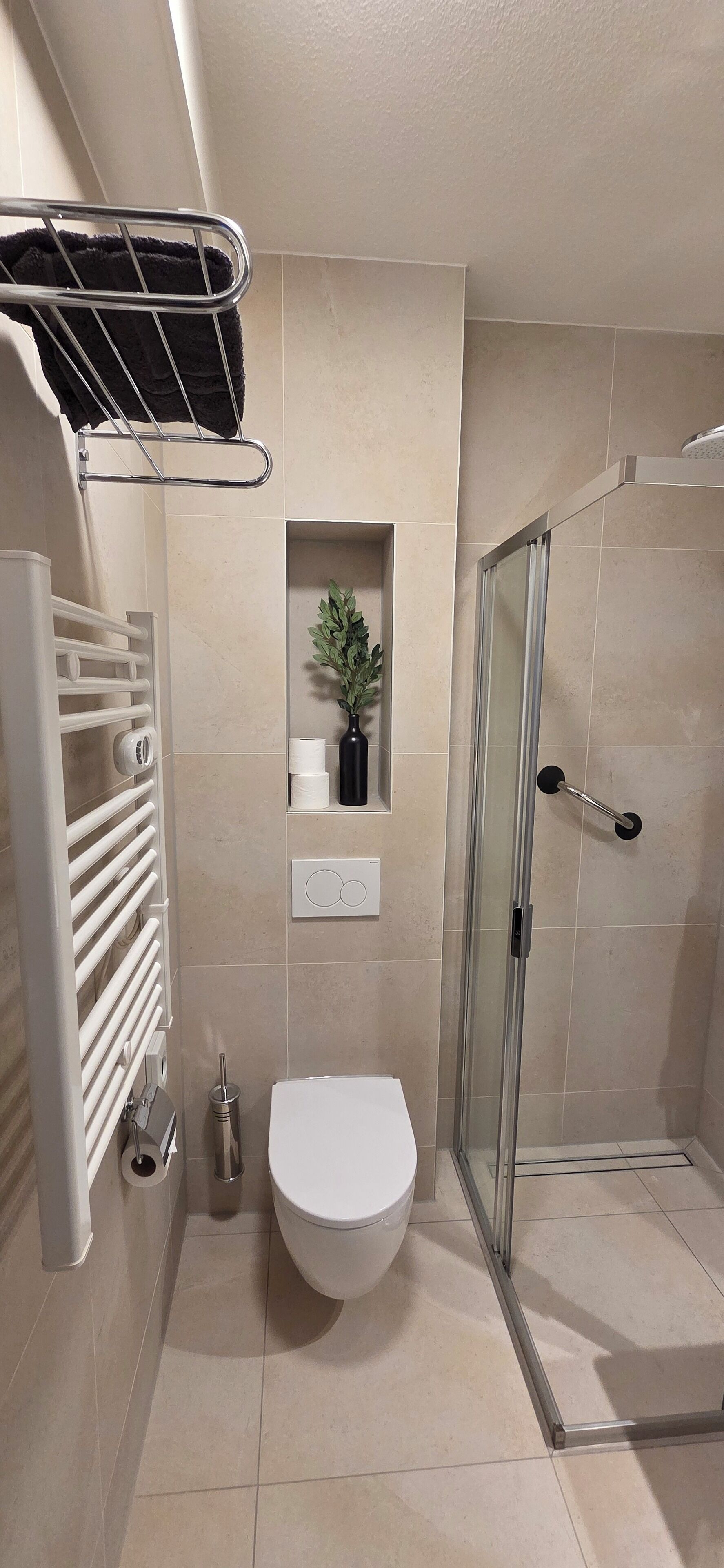 Un baño moderno con inodoro, ducha y barra para toallas.