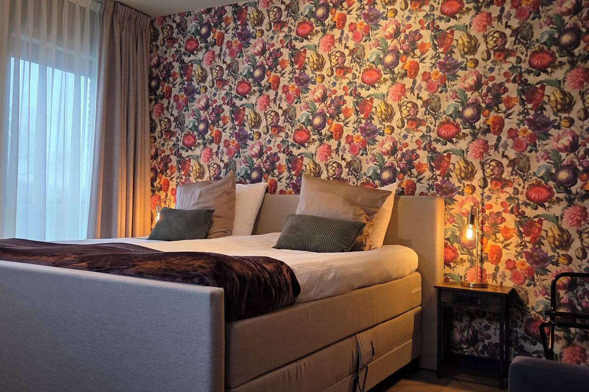 Un dormitorio con cama, mesita de noche y pared con estampado floral.