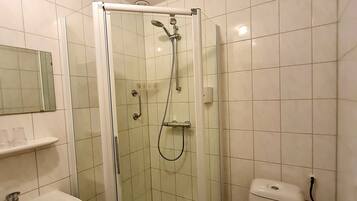 Een badkamer met een douche met glazen wand, toilet en wastafel.