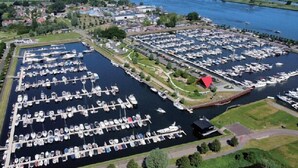 A marina with numerous boats docked in a structured layout, surrounded by greenery and residential areas. - Hotel 't Trefpunt (Made)