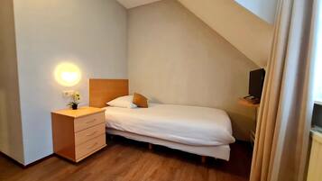 A bedroom with a bed, a nightstand, a lamp, and a TV.