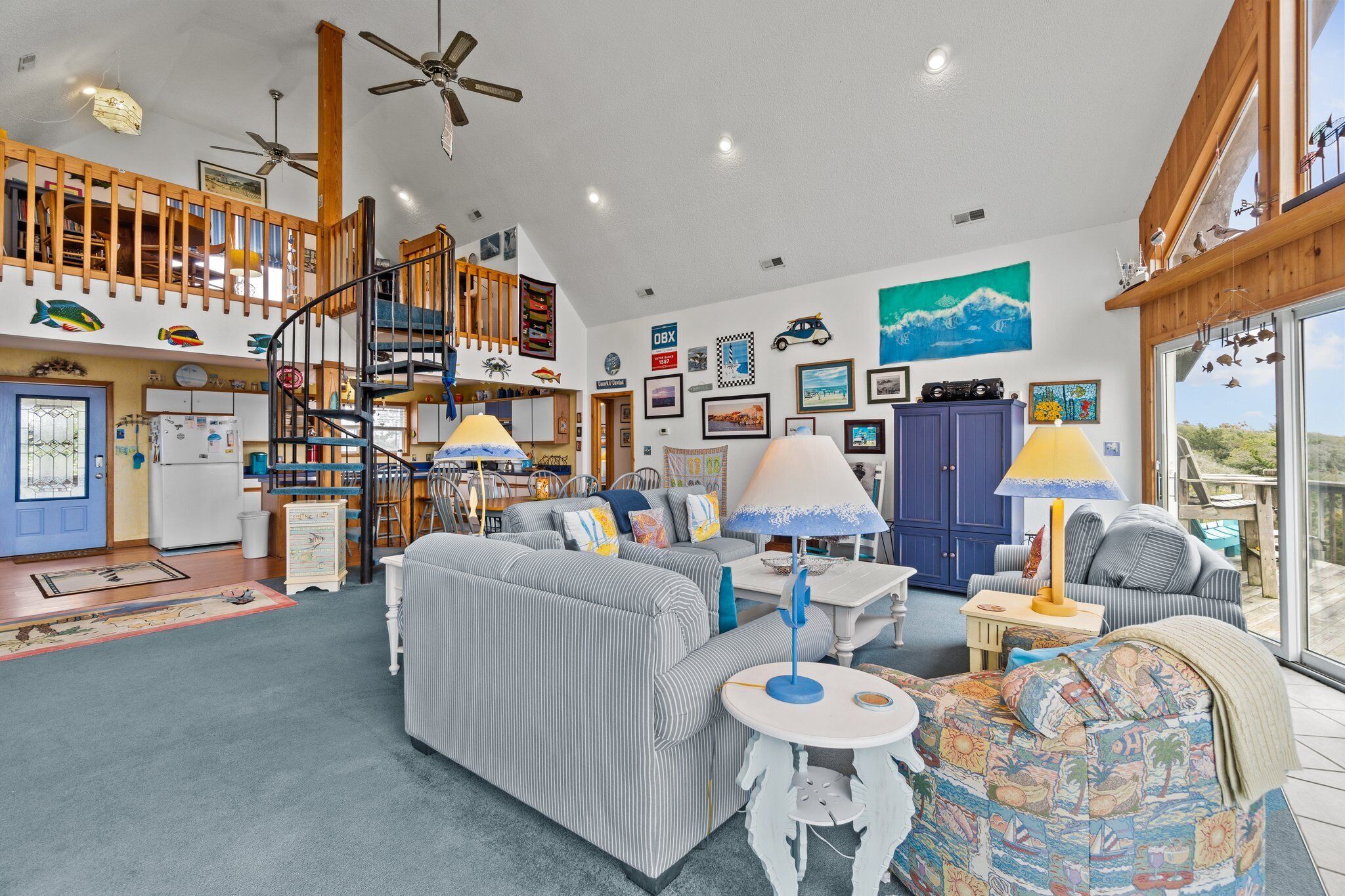 A spacious living area with a high ceiling, a staircase, and a balcony with a view.