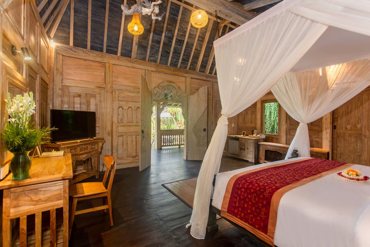 A wooden room with a bed, a desk, and a television.