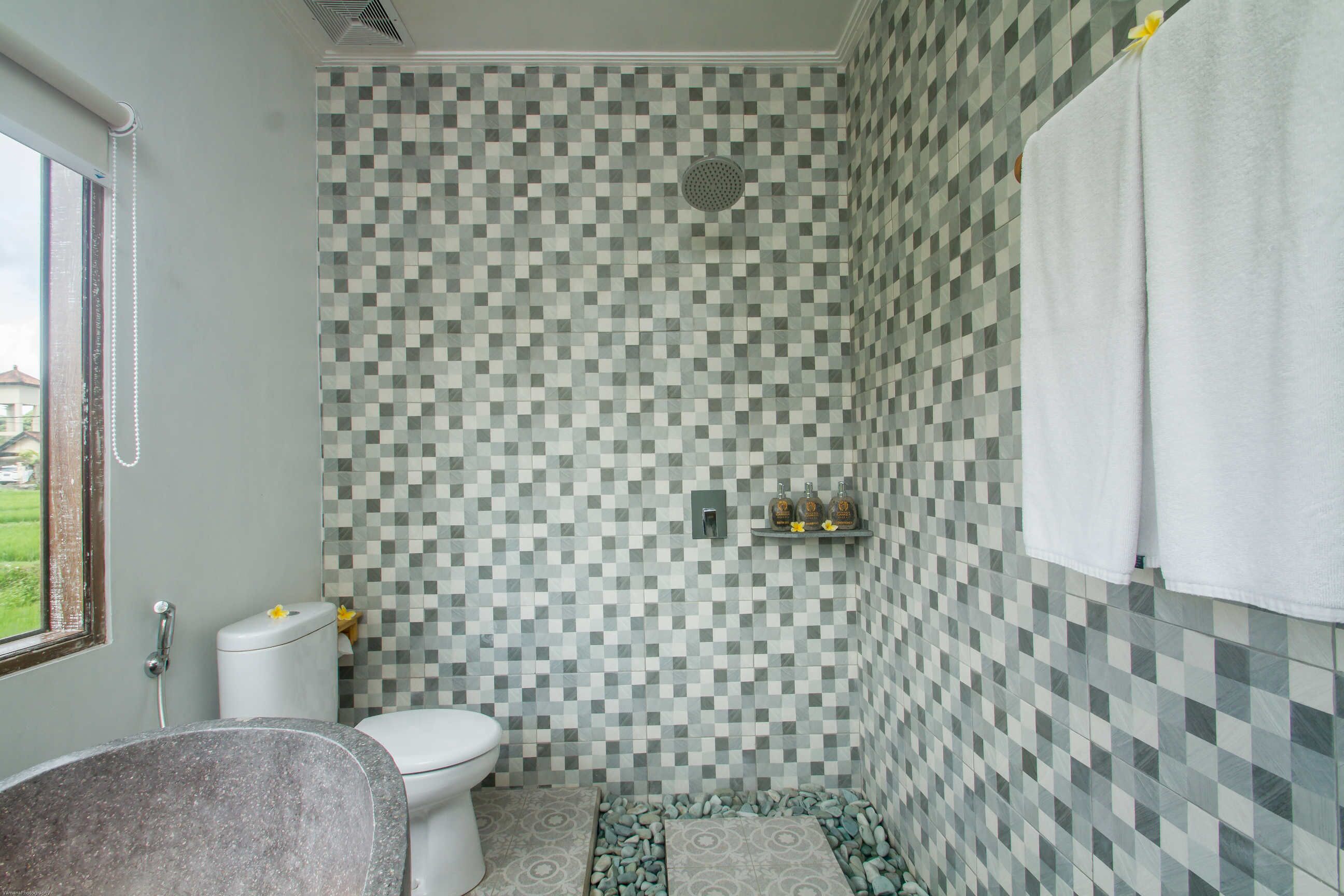 Un baño con pared de baldosas a cuadros, un inodoro, una ducha y una bañera.