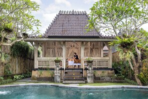 A traditional wooden structure with a tiled roof, a pool, and a person receiving a massage. - Wooden Ganeca Villas by GenuineHost (Tegallalang)