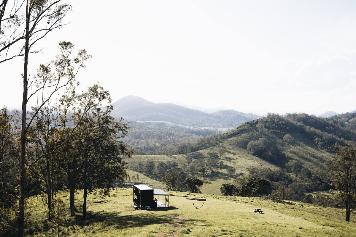 A remote cabin in a hilly landscape with a clear view of distant mountains.