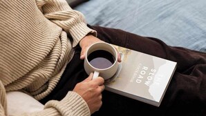 Una persona sosteniendo un libro titulado 'The Slow Road' y una taza de té.