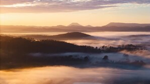 A landscape with a mountain range in the distance, a valley with trees, and a body of water. - Tiny Heidi Summary:<br>T (Bollier)