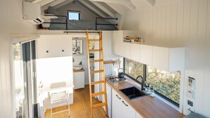 A compact kitchen with a wooden countertop, a sink, and a window overlooking greenery. - Tiny Heidi Summary:<br>T (Bollier)