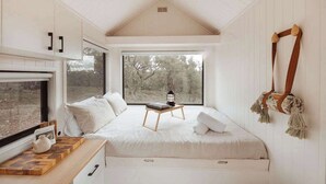 A bedroom with a bed, a window, a wooden table, and a hanging decoration.