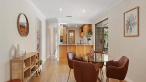 A modern kitchen with wooden cabinets and a glass door leading to the dining area. - Southern Vales by Wine Coast Holiday Rentals (WILLUNGA SOUTH)