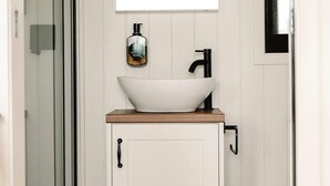 A bathroom with a white cabinet, a white sink, and a ceiling fan. - Tiny Mowgli Summary: (Bulliac)