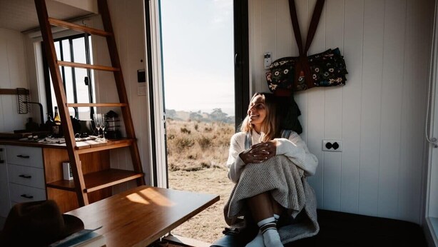 A cozy room with a wooden desk, a ladder, and a large window offering a view of the outdoors. - Tiny Ruby - Central West (Duramana)