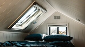 A bedroom with a sloped ceiling, skylight, and a window. - Tiny Ruby - Central West (Duramana)