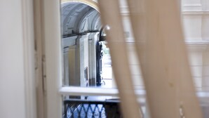 A view through a window with a metal grille, leading to an interior space with a white wall and a partially visible archway. - Da Francesco (Naples)