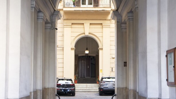 A building entrance with two parked cars and a balcony above. - Da Francesco (Naples)