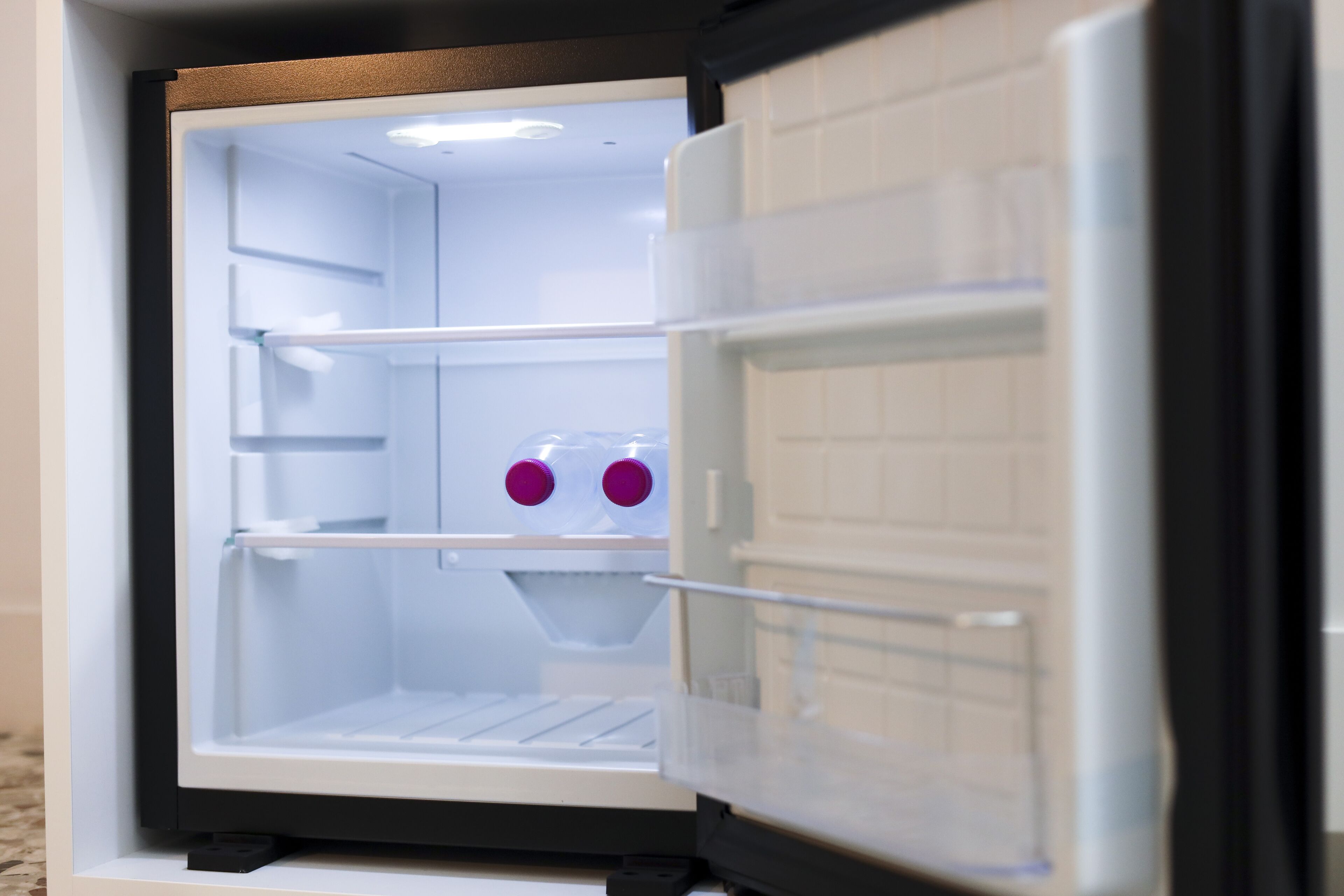 An open refrigerator with shelves and a water dispenser.