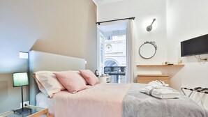 A modern bedroom with a bed, bedside table, lamp, and a view of the city through an open window. - Da Francesco (Naples)