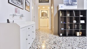 A hallway with a white cabinet, a black shelving unit, and framed pictures on the walls. - Da Francesco (Naples)
