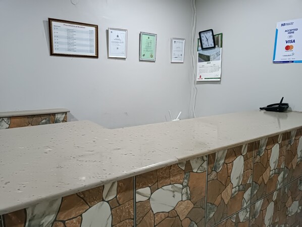 A reception desk with a stone-patterned counter, framed documents on the wall, and a Visa acceptance sign. - Stadium View Executive Guest House (Lilongwe)
