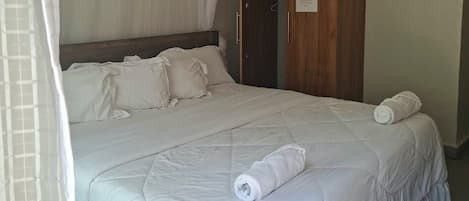 Un dormitorio con cama, armario de madera y dosel blanco.