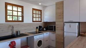 Een kleine keuken met een wasmachine, een magnetron en een koelkast.