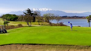 A golf course with a clear view of a lake and mountains in the background.