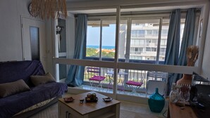 A living room with a sofa, coffee table, and a balcony with chairs and a table.