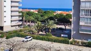 A residential area with a white building, a parking lot, and a view of the sea.