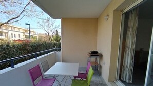 A balcony with a white table and two chairs, one pink and one green. - Spacious apartment in Argelès, terrace + private parking (Argelès-sur-Mer)