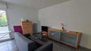 A modern living room with a sofa, a television, a cabinet, and a small table. - Spacious apartment in Argelès, terrace + private parking (Argelès-sur-Mer)