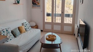 Un salon avec un canapé, une table basse, un téléviseur et une affiche accrochée au mur.