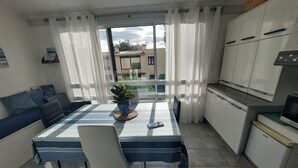 A compact living space with a dining table, chairs, a sofa, and a kitchen area. - Air-conditioned 2-room apartment 4/5 pers with pool (Argelès-sur-Mer)