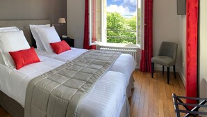 A hotel room with a large bed, red pillows, a chair, and a window with a view of greenery. - Manoir de Montigny (Russy-Bémont)