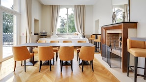 A spacious dining area with a long table and several chairs, large windows with curtains, and a fireplace. - Manoir de Montigny (Russy-Bémont)