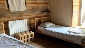 Una habitación con dos camas de madera, una mesita de noche de madera, una ventana con vistas y un armario de madera.