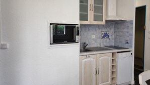 A compact kitchen with a microwave, sink, and a dishwasher. - Ground Floor 2-Room Apartment Near Beach & Shops, Sleeps 4 (Argelès-sur-Mer)
