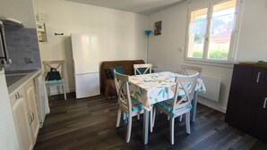 A compact kitchen with a dining table, chairs, a refrigerator, and a window with a view. - Ground Floor 2-Room Apartment Near Beach & Shops, Sleeps 4 (Argelès-sur-Mer)