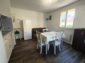 A compact kitchen with a dining table, chairs, a refrigerator, and a window with a view.