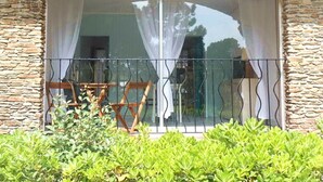 A room with a stone wall, a large window with curtains, and a view of the outside.