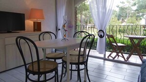 A balcony with a table and chairs, a television, and a lamp.