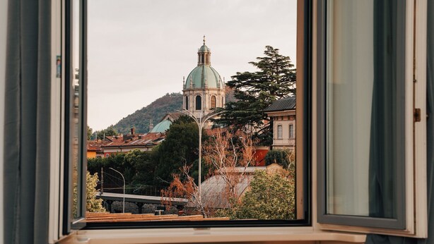 A view from a window overlooking a historic building with a dome, surrounded by trees and other buildings.